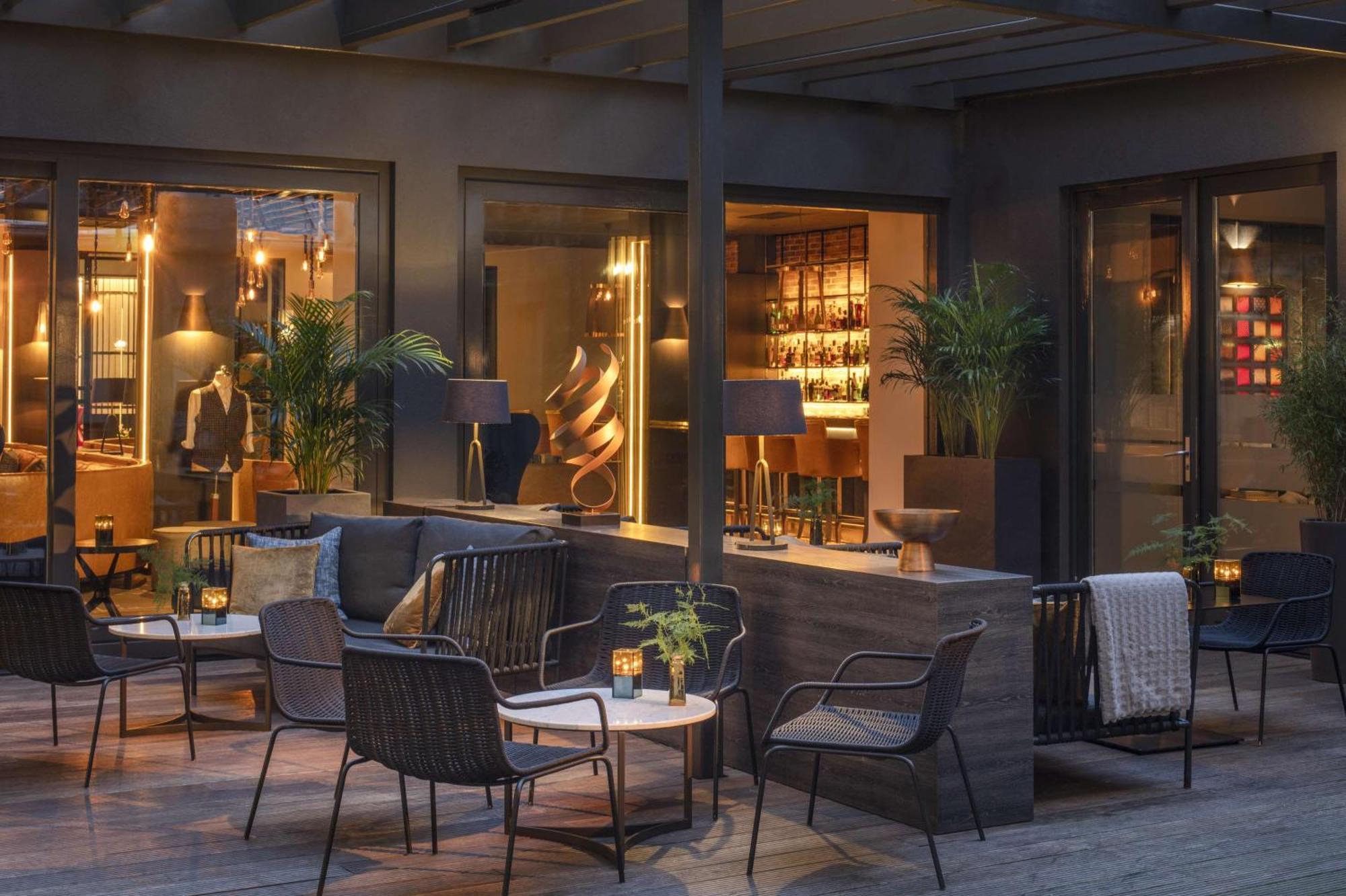 Anantara Grand Hotel Krasnapolsky Amesterdão Exterior foto The photo depicts a stylish and modern outdoor seating area. It features a combination of comfortable chairs and small tables arranged around a cozy space. The setting is illuminated with soft lighting, creating an inviting atmosphere. In the backgro