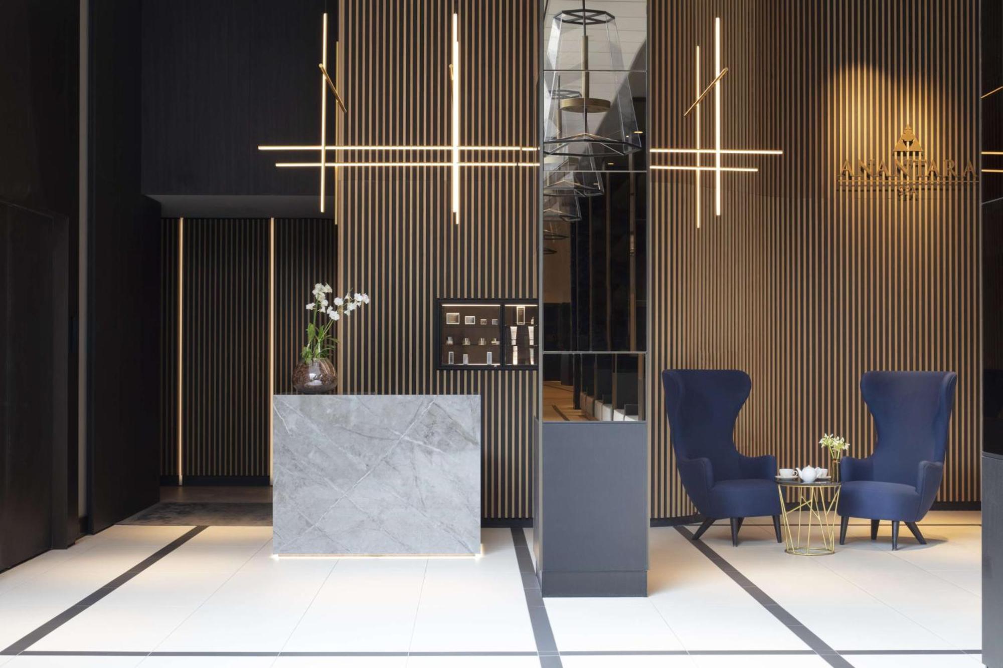 Anantara Grand Hotel Krasnapolsky Amesterdão Exterior foto The photo shows a modern reception area, likely in a hotel or office. It features a clean and stylish design with vertical wooden slats on the walls. 

A grey marble reception desk is positioned prominently, accompanied by a stylish black display or 